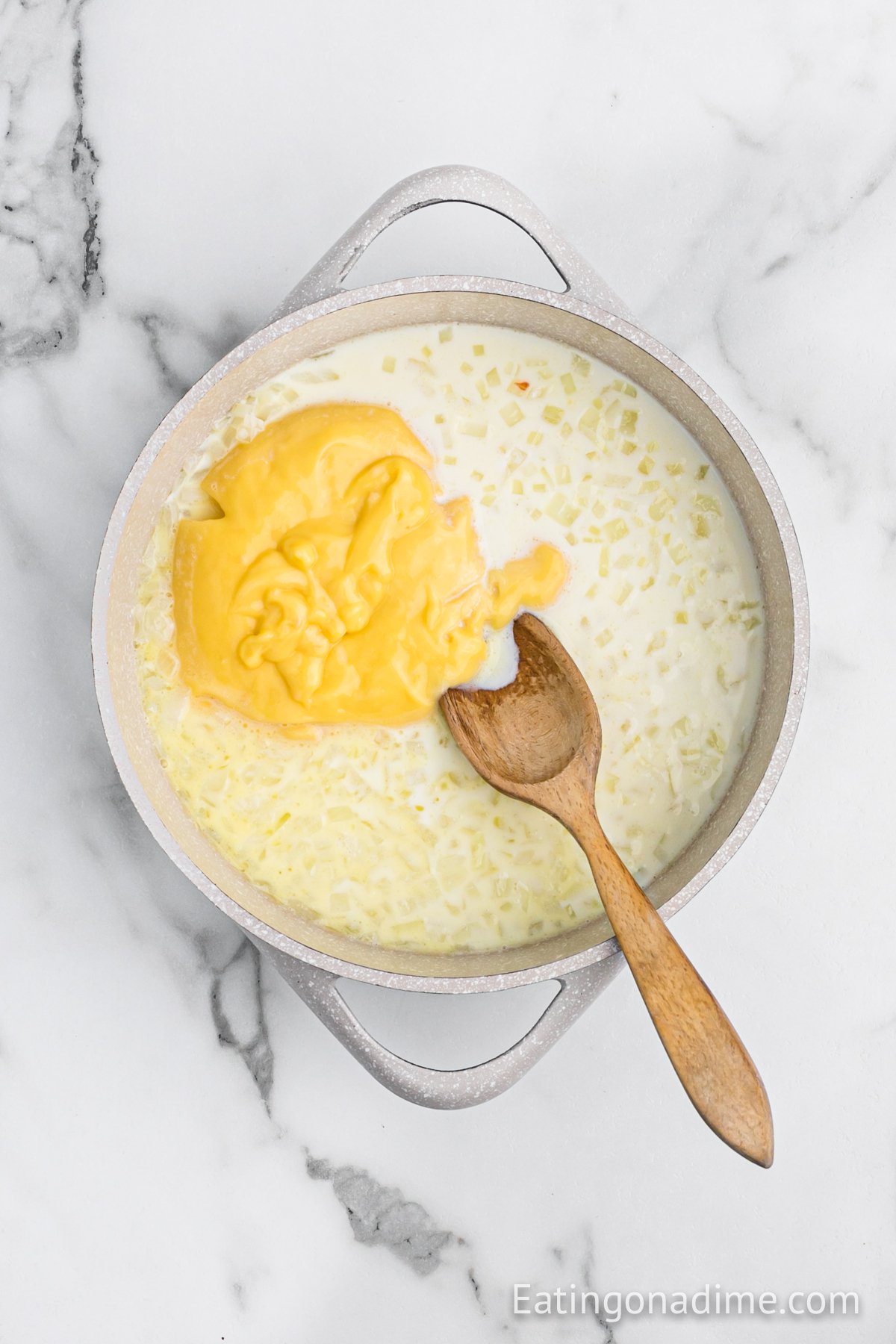 Stirring in the cream of chicken soup in with the melted butter with the onions