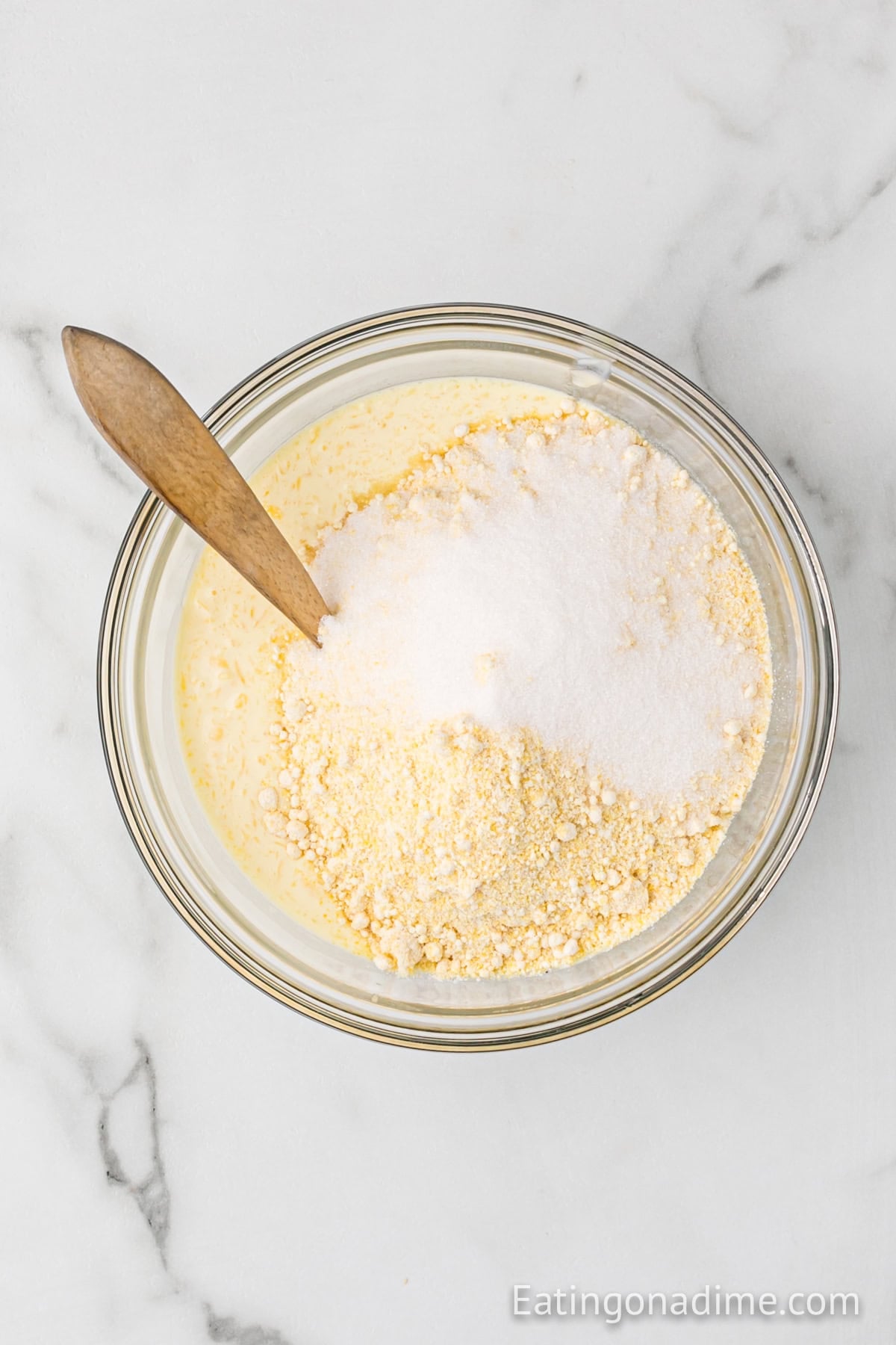 Sugar and jiffy mix added to the wet ingredients in a bowl.