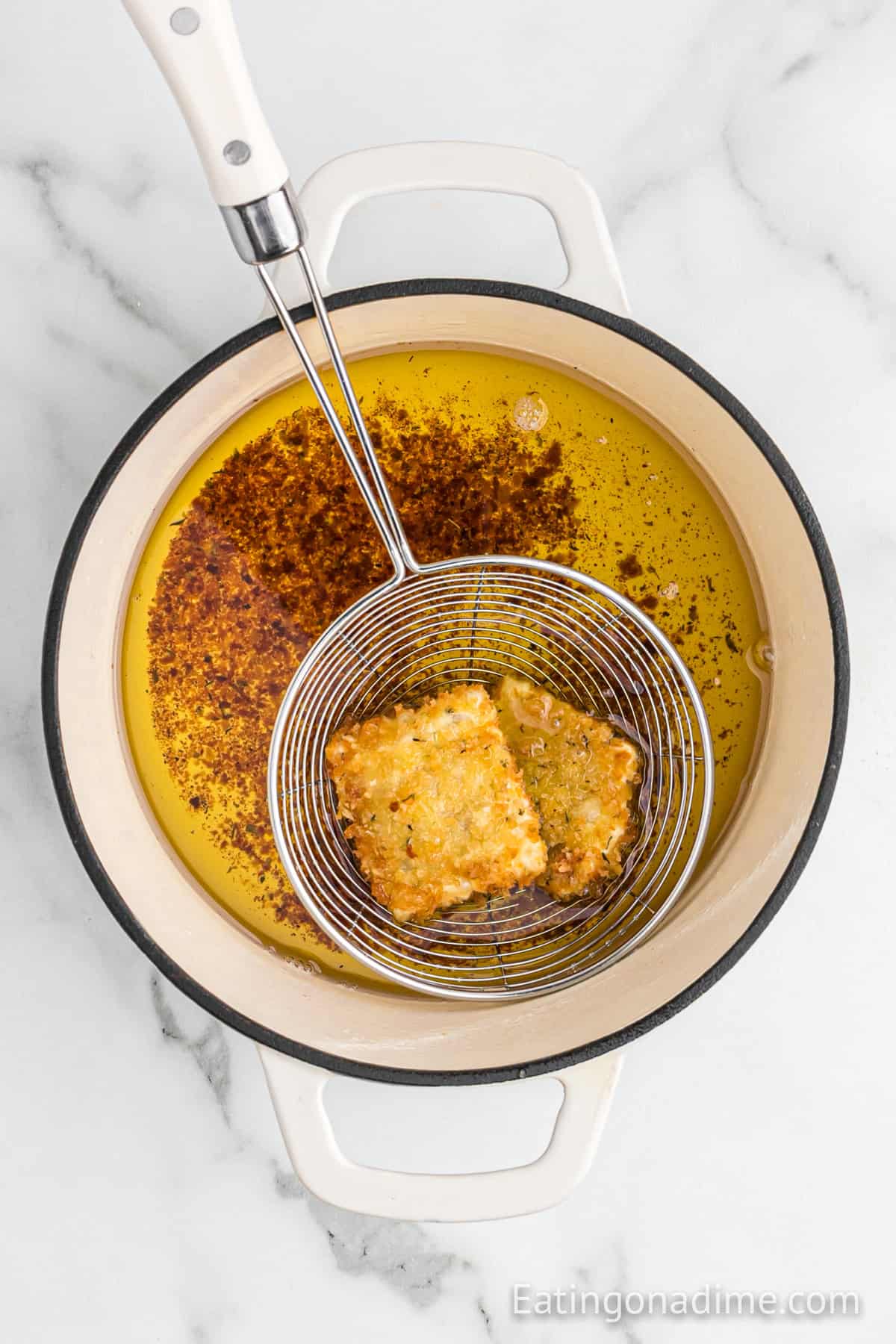 Fried ravioli in a large pot of oil.