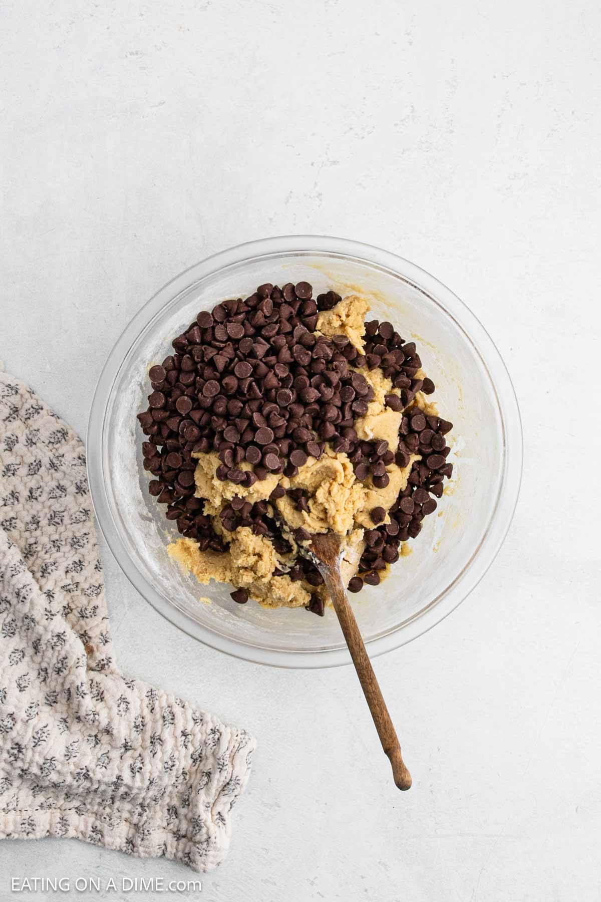 Chocolate chips are added to the cookie dough in a bowl.