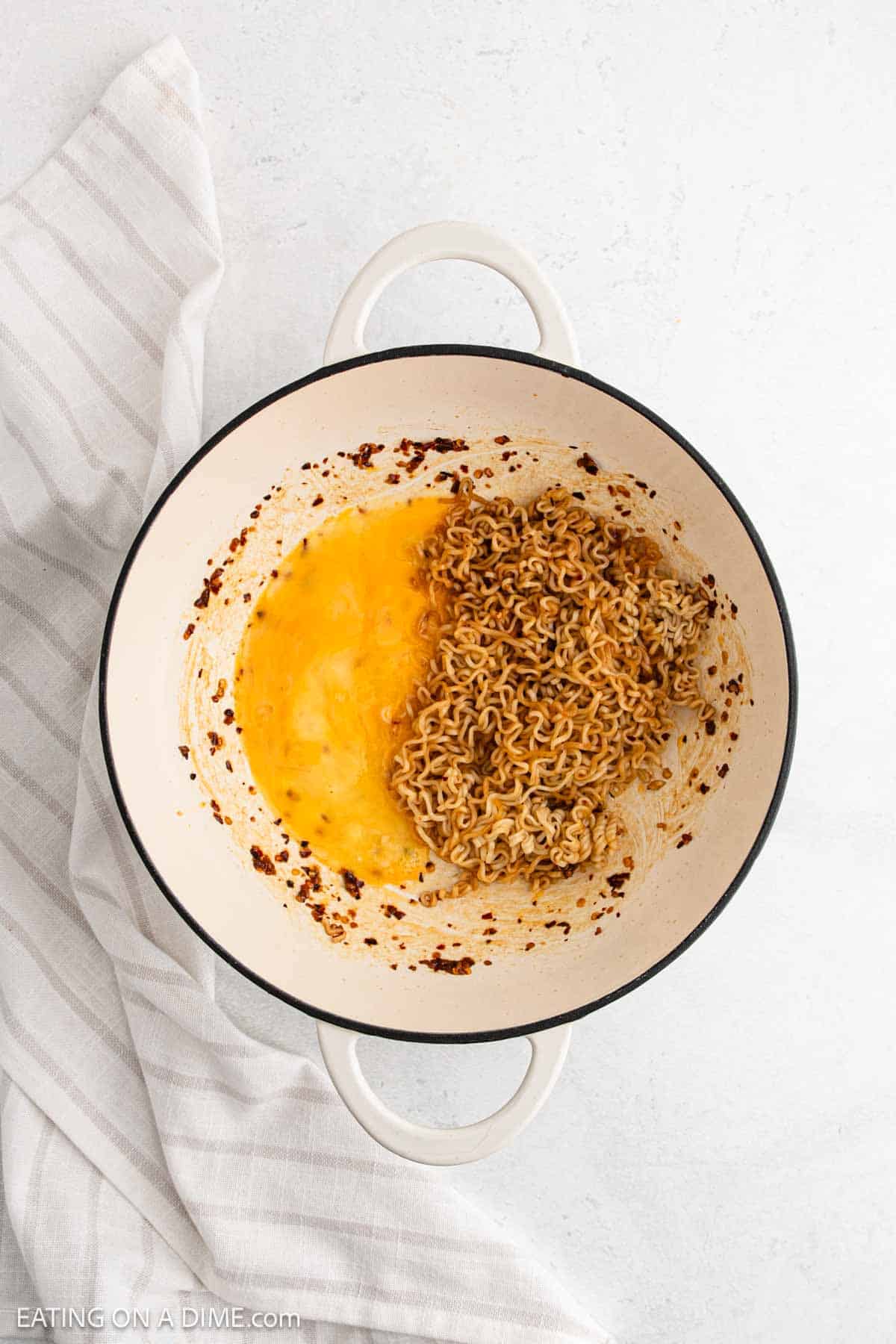 Adding scrambled eggs to the large pot with the cooked ramen noodles mixture