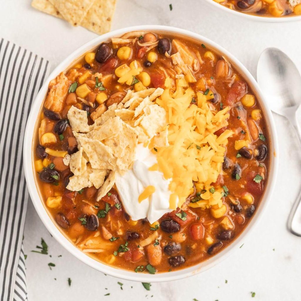Taco Soup in a bowl topped with cheese, chips, and sour cream