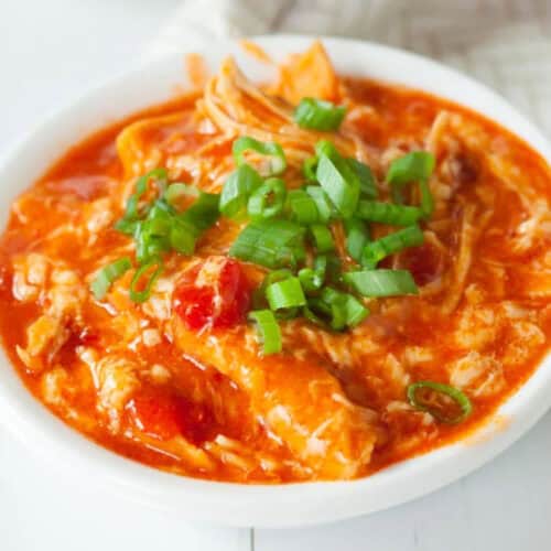 A white bowl filled with crock pot buffalo chicken enchilada casserole.
