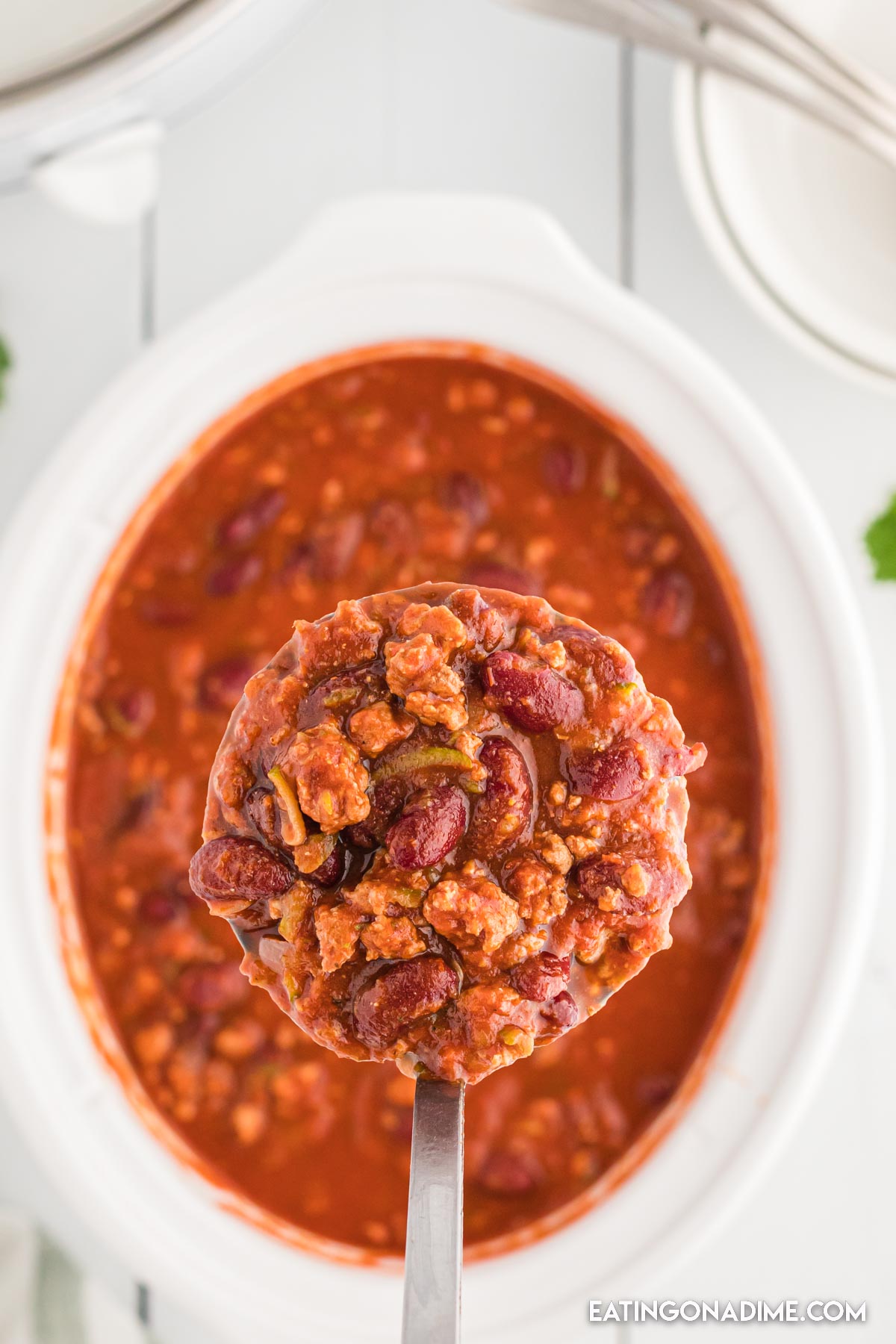 Turkey chili in a slow cooker with a serving on a ladle