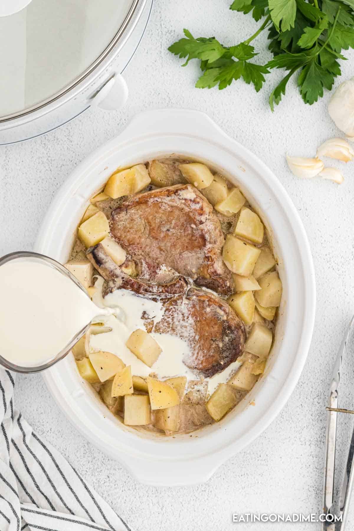 Heavy cream pouring into the pork chops with the potatoes.