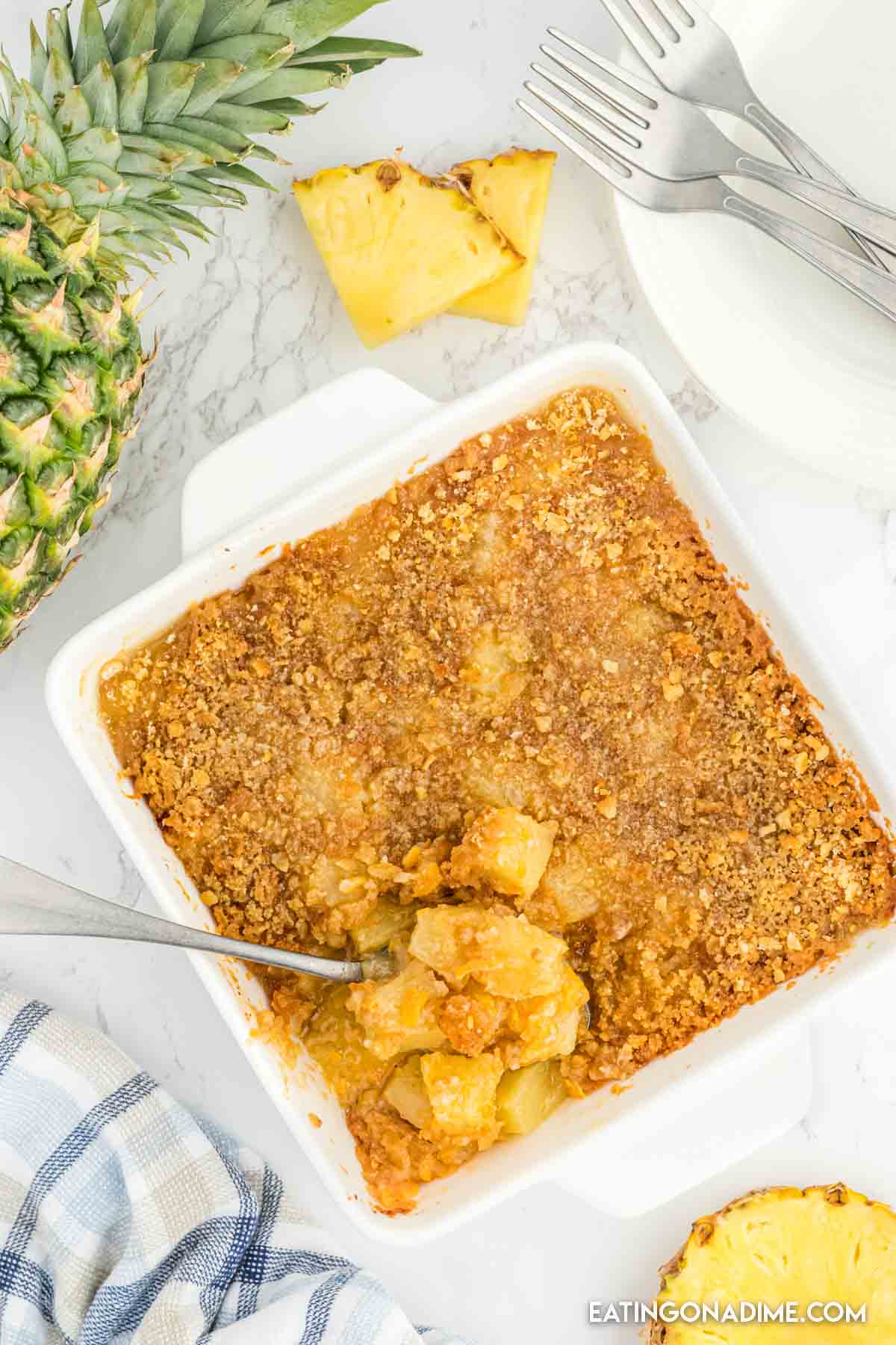 Close up image of pineapple casserole in a baking dish with a spoon