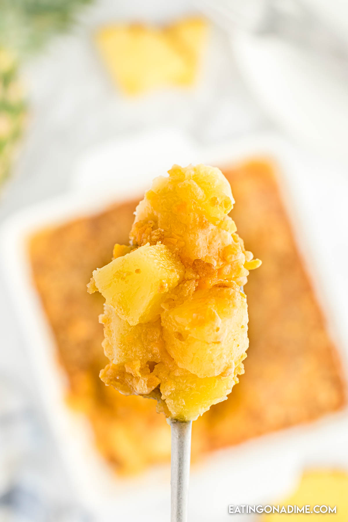 Close up image of pineapple casserole with a serving on a spoon