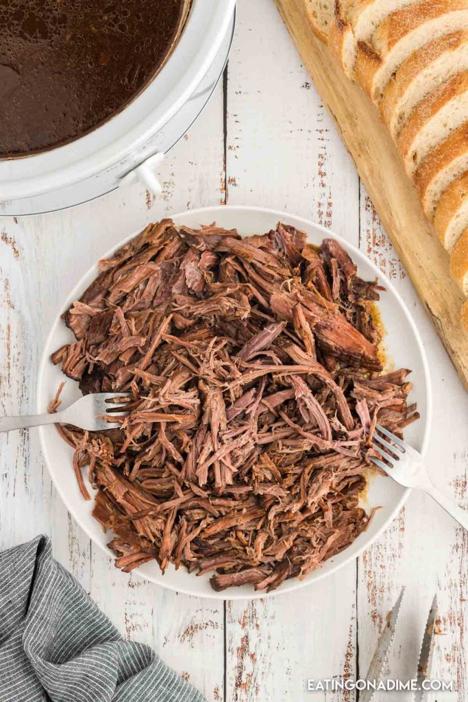 Shredded roast beef on a plate with two forks