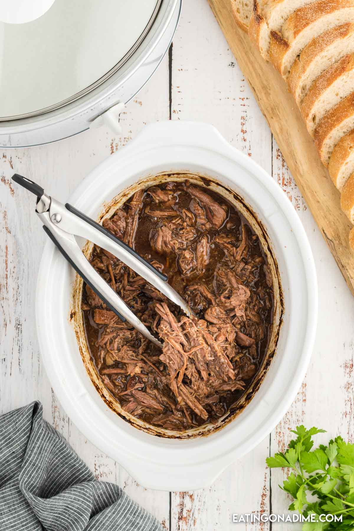Shredded roast beef in the slow cooker with tongs