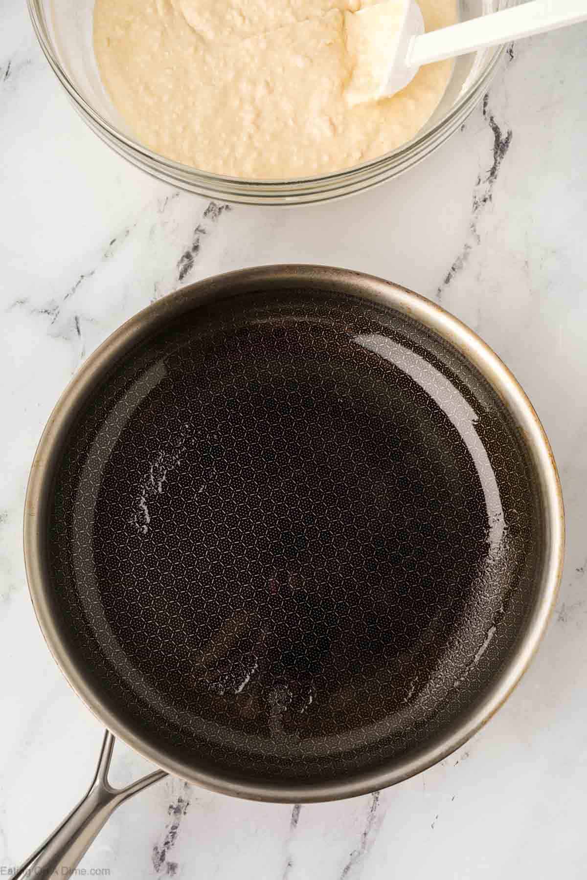 Oil in a large skillet with a bowl of the pancake mixture on the side