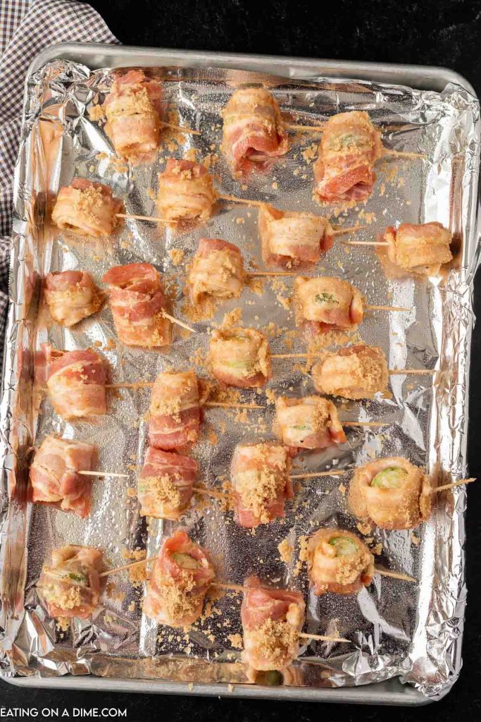 Bacon Wrapped Brussel Sprouts uncooked on a baking sheet lined with foil