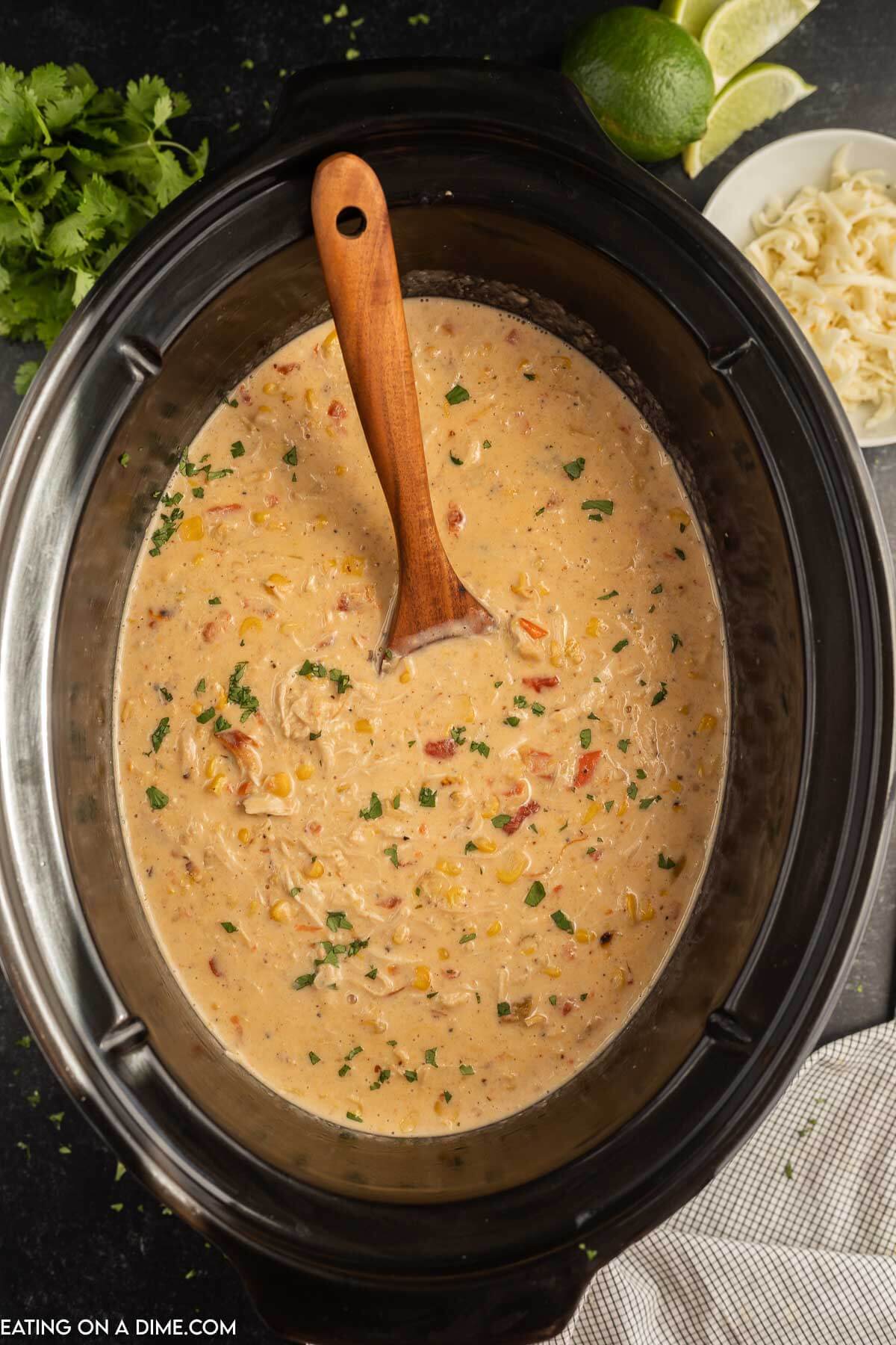 Mexican Corn Chowder in the slow cooker with a wooden spoon