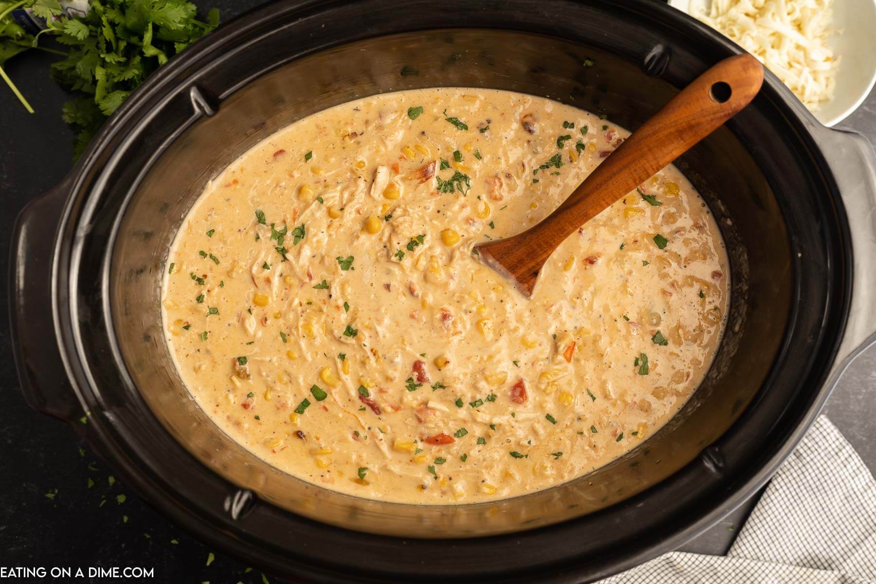 Mexican Corn Chowder in a slow cooker with a wooden spoon