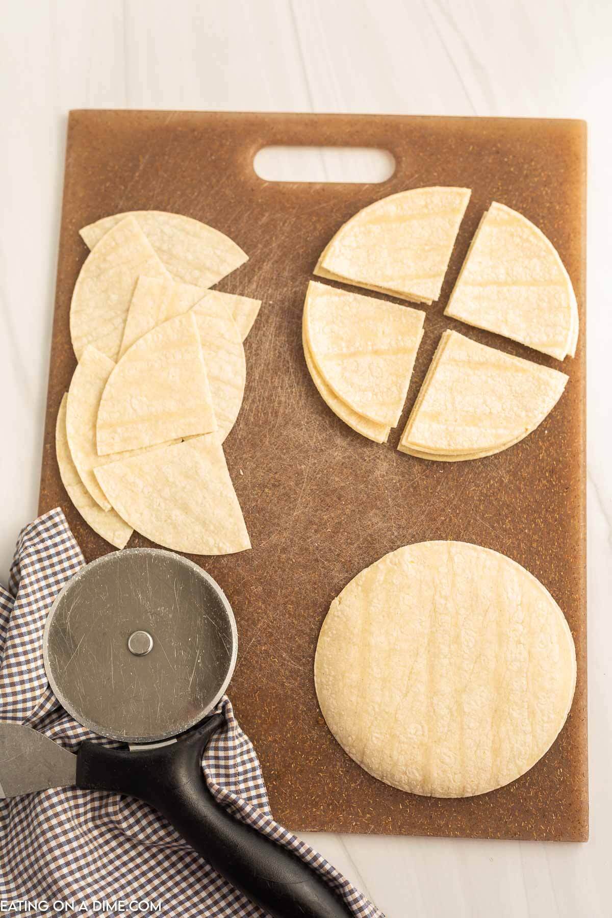 Cutting corn tortillas in triangles on a cutting board with a pizza cutter
