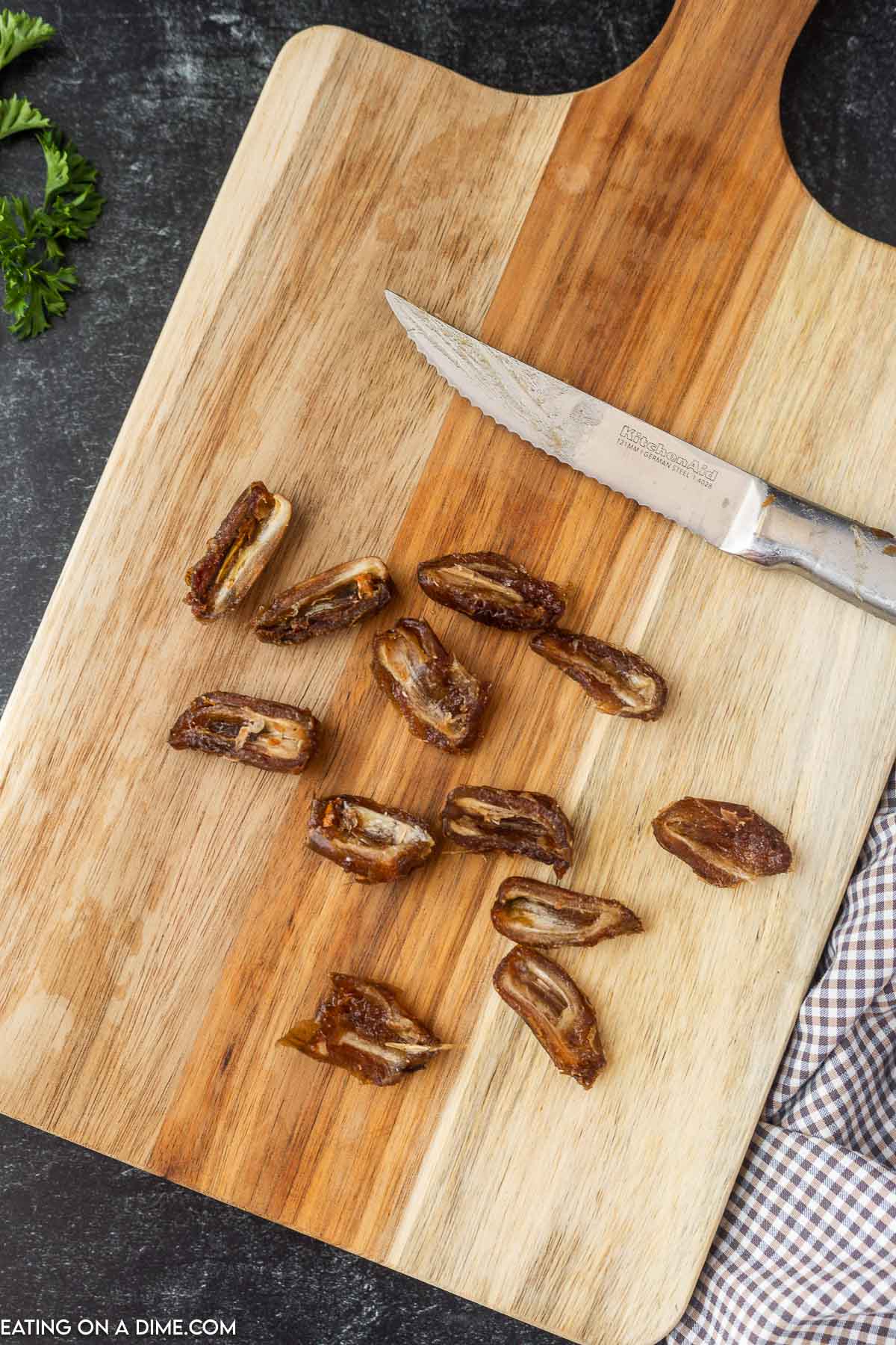 Cut Dates in half on a cutting board with a knife