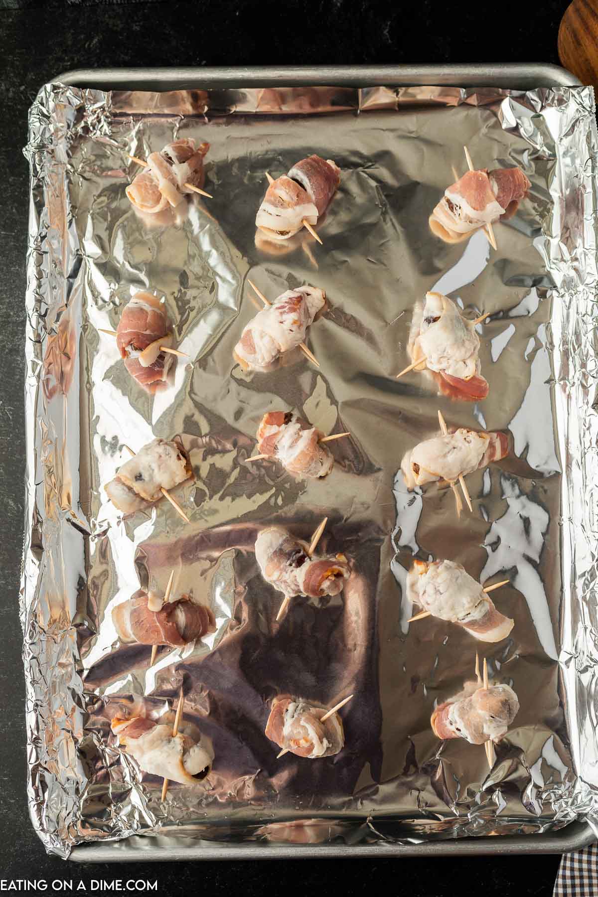 Bacon Wrapped Dates on a baking sheet lined with foil