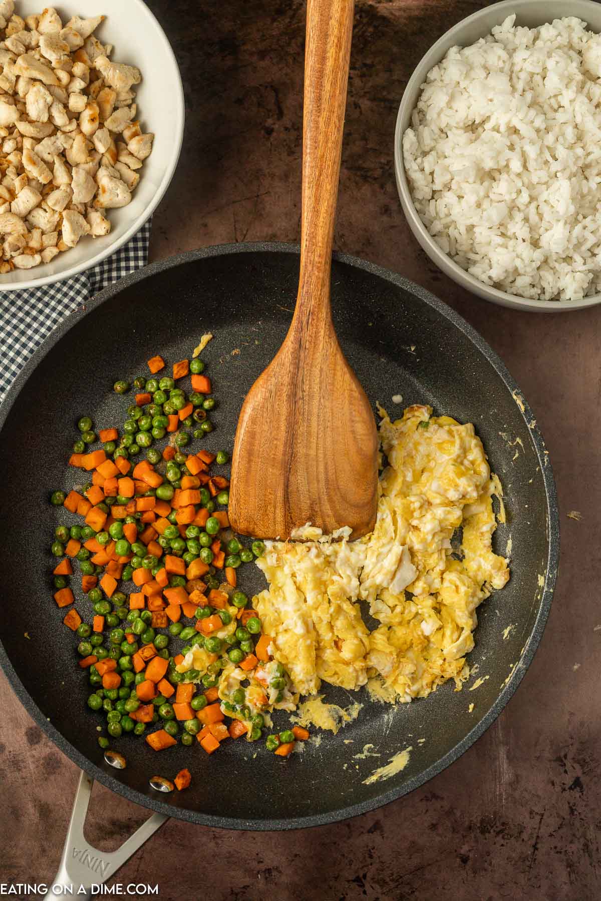 Cooking the vegetables and scrambling eggs in a skillet with a wooden spoon