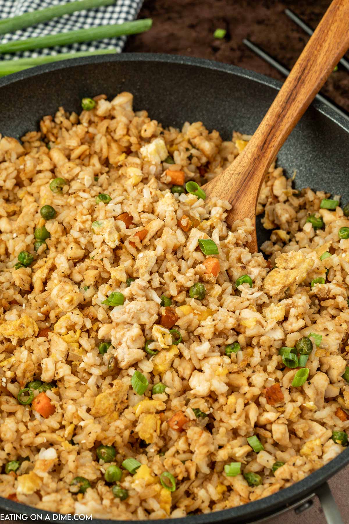 Chicken Fried Rice in a skillet with a wooden spoon