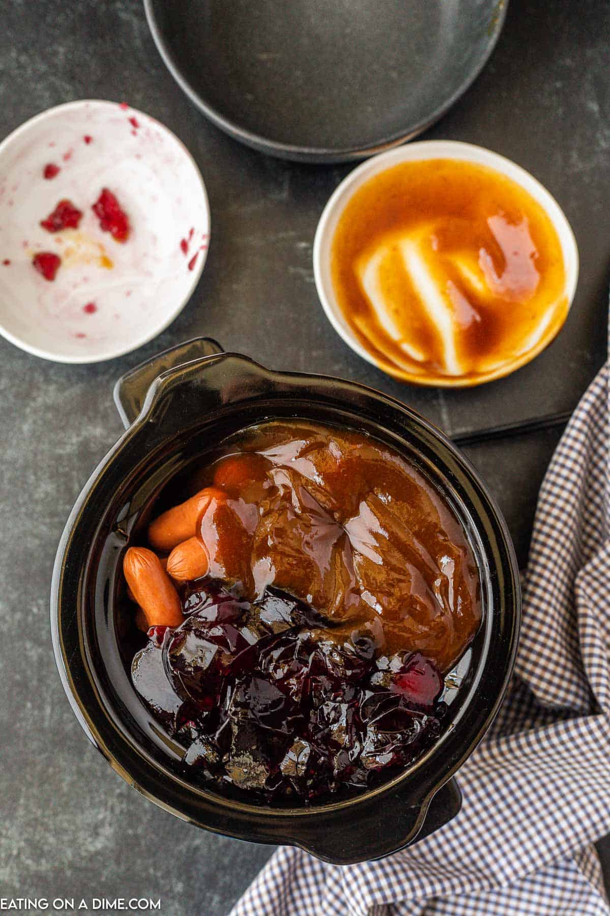 Mini crock pot filled with little smokes and topped with jelly and BBQ sauce