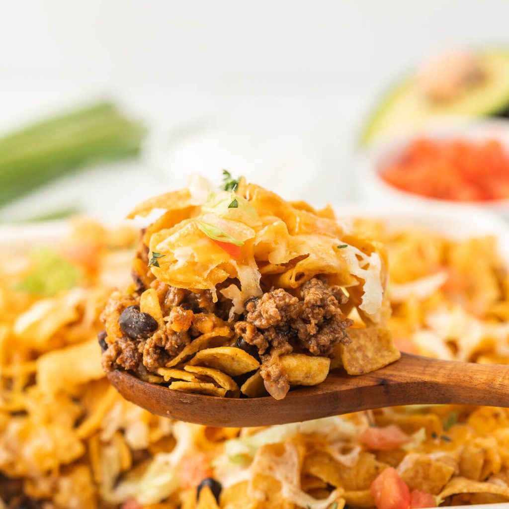 Walking Taco Casserole topped with a serving on a wooden spoon