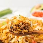 walking taco casserole being scooped by a wooden spoon.