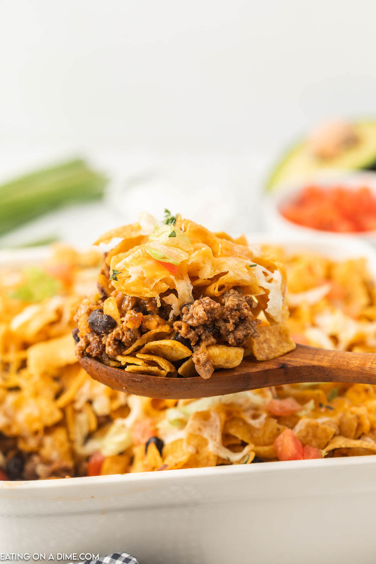Walking Taco Casserole topped with a serving on a wooden spoon