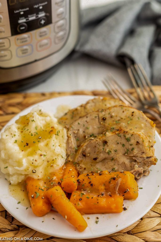 Pork Roast sliced on a plate with mashed potatoes and carrots