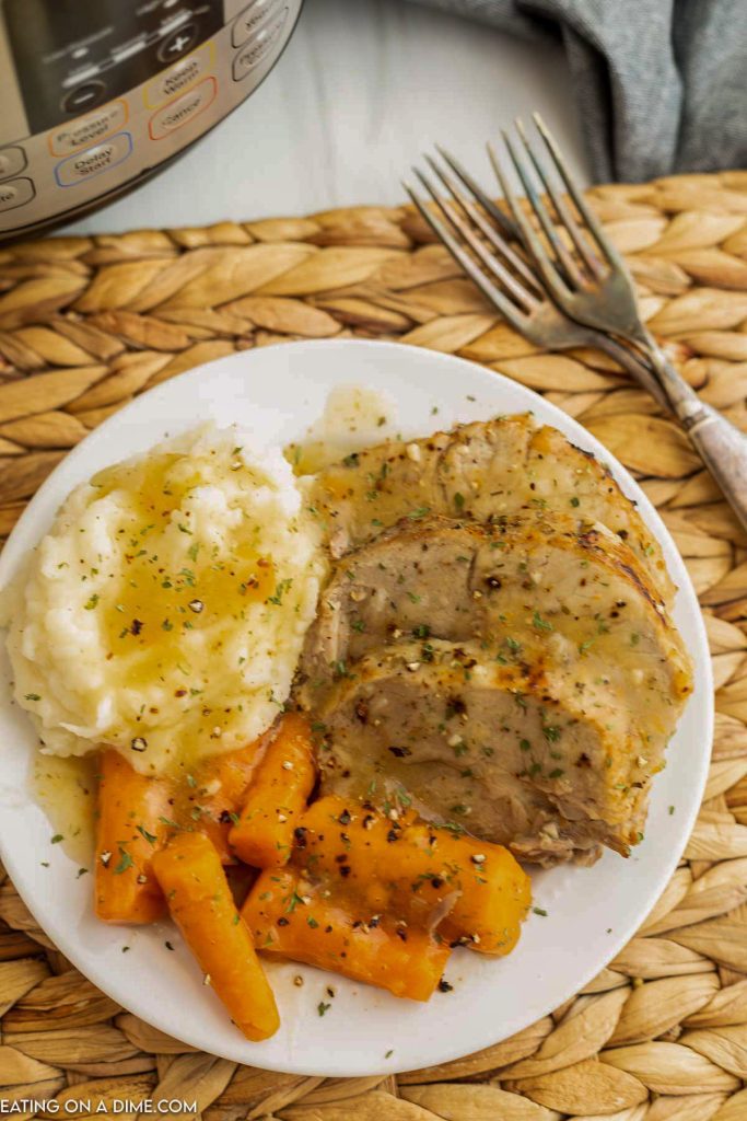 Pork Roast sliced on a plate with mashed potatoes and carrots