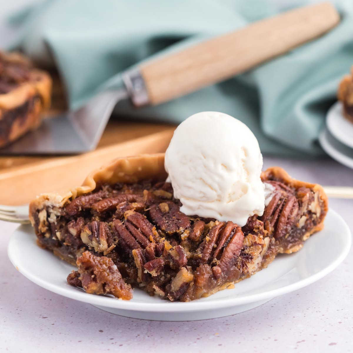 A slice of pecan pie on a white plate with ice cream