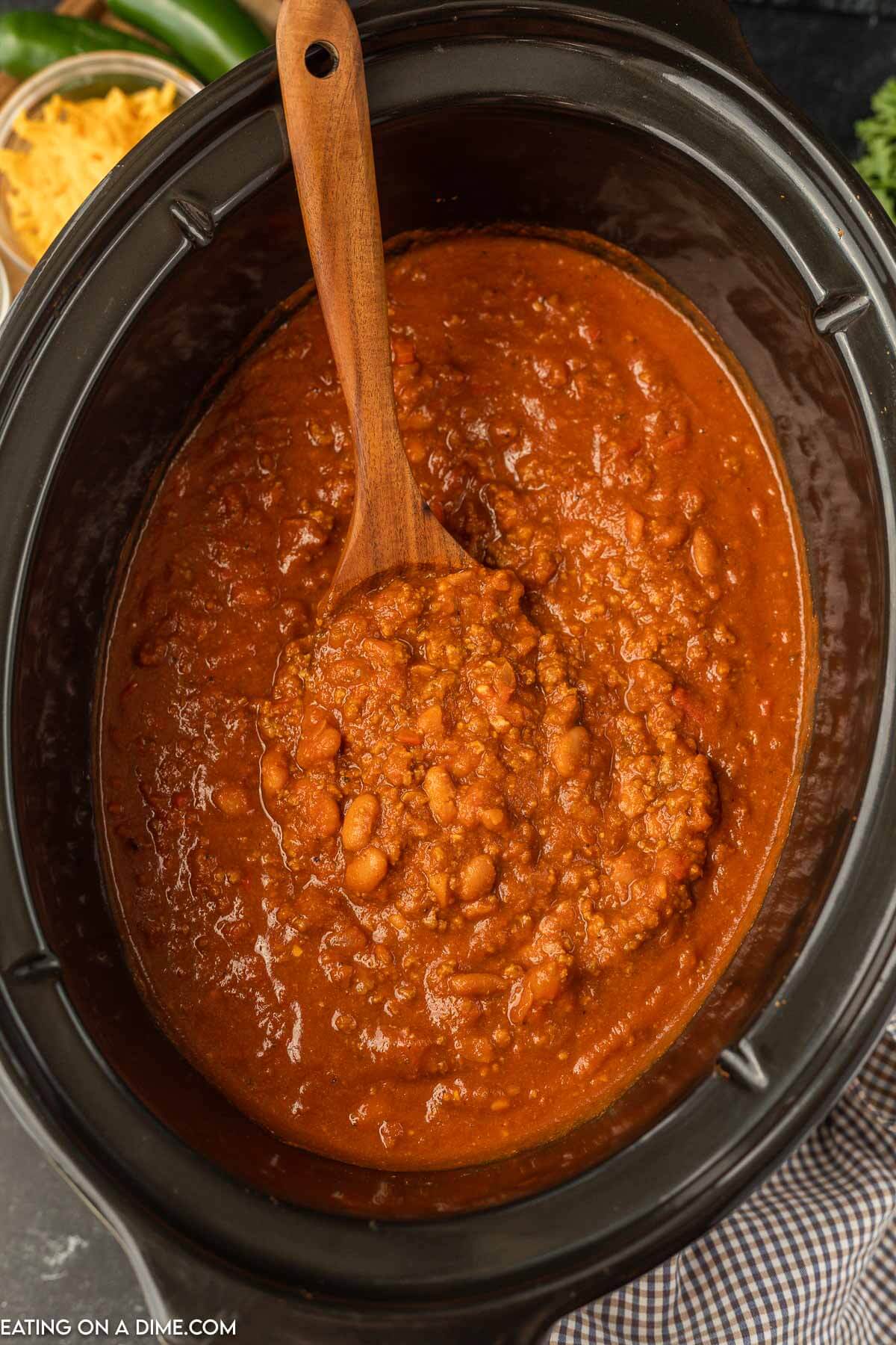 Pumpkin chili in the slow cooker with a wooden spoon