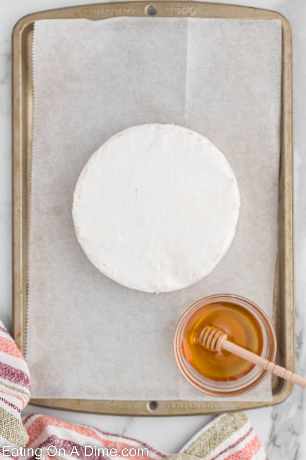 Brie on a baking dish with a bowl of honey on the side