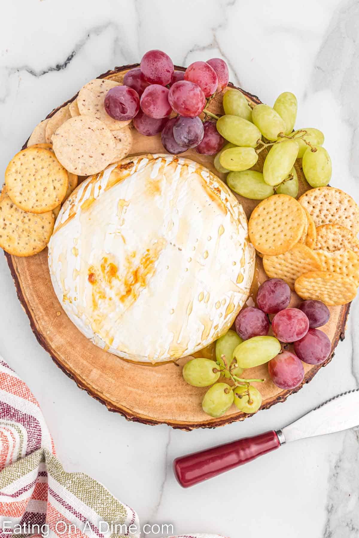 Baked brie on a platter with a side of grapes and crackers