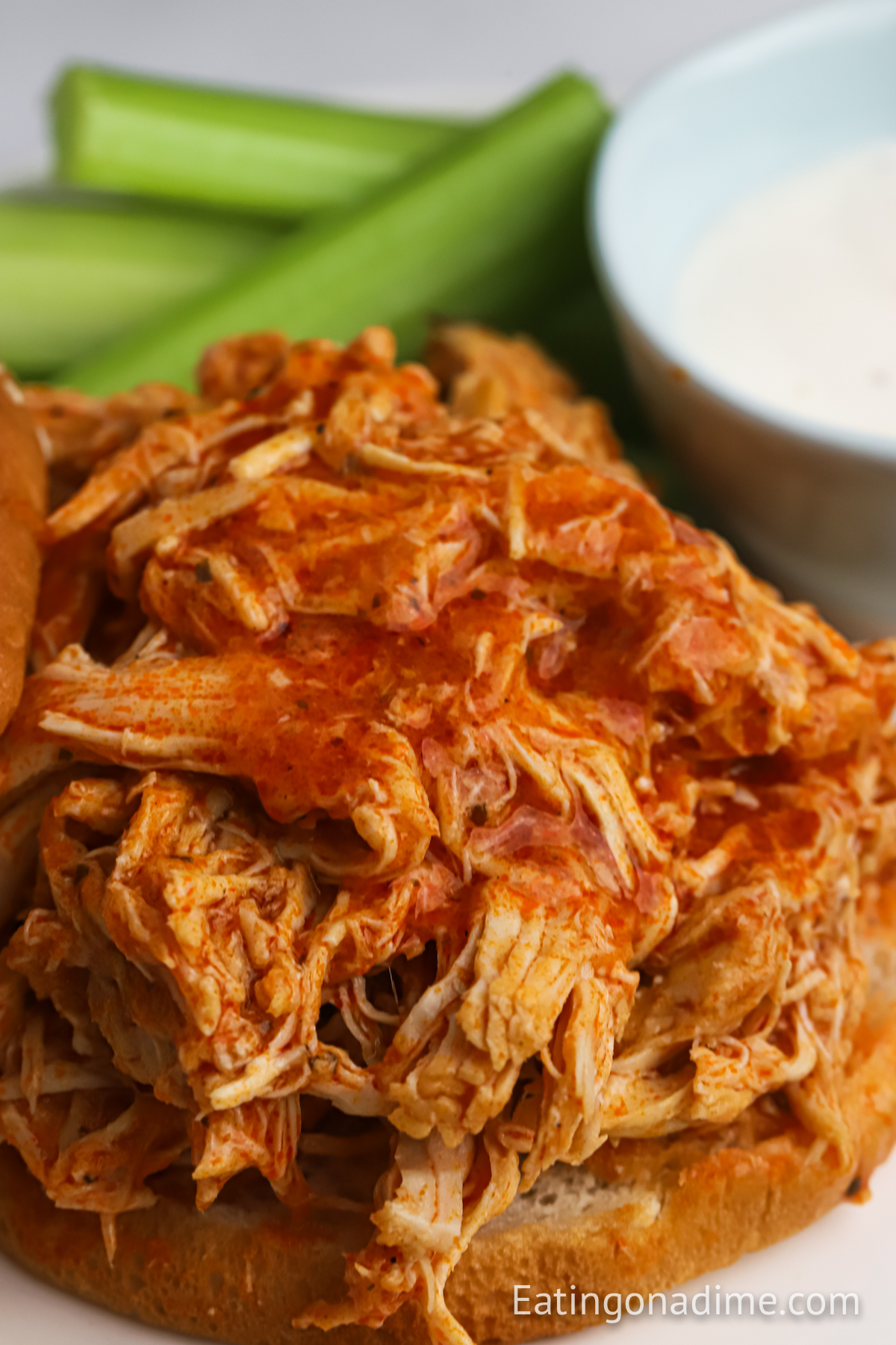 Close up image of buffalo chicken in a sandwich with a side of ranch and celery
