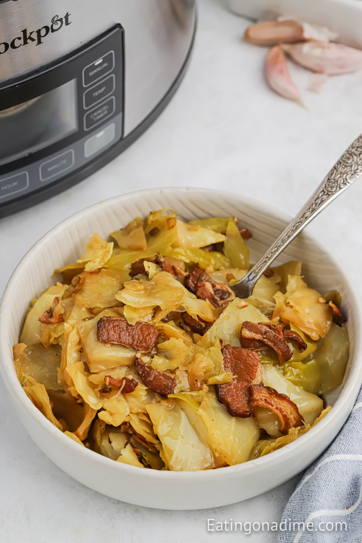 Close up image of cooked cabbage in a bowl with bacon and a silver spoon