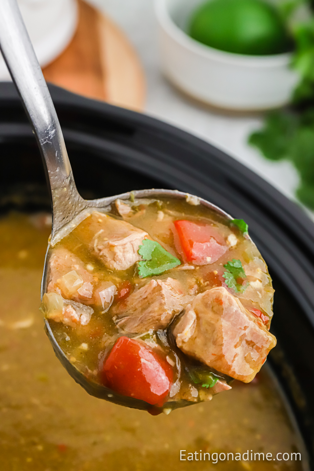 Chile Verde in a slow cooker with a serving on a ladle