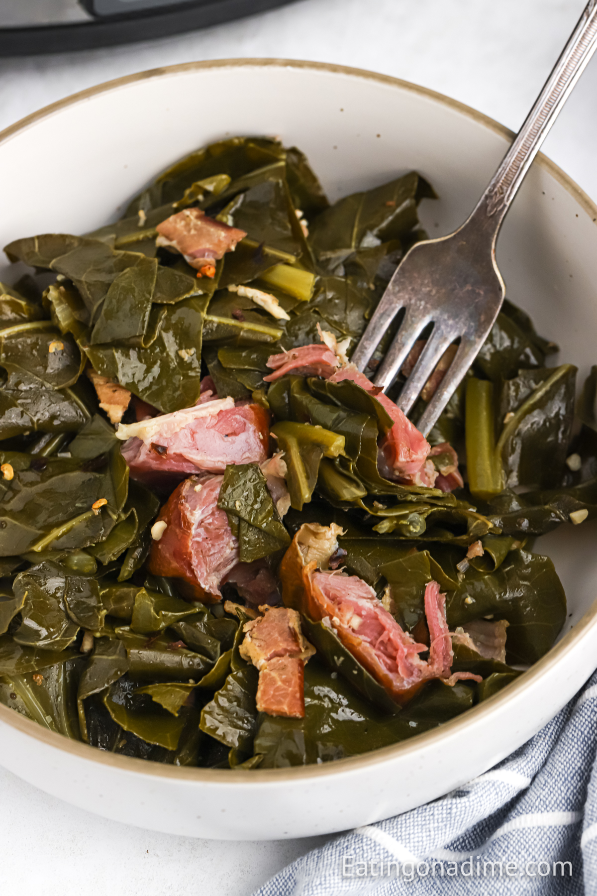 Collard greens with ham hock in a bowl with a fork