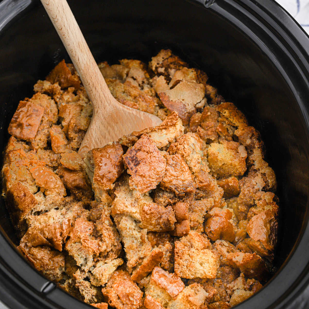 French Toast Casserole in a slow cooker with a wooden spoon