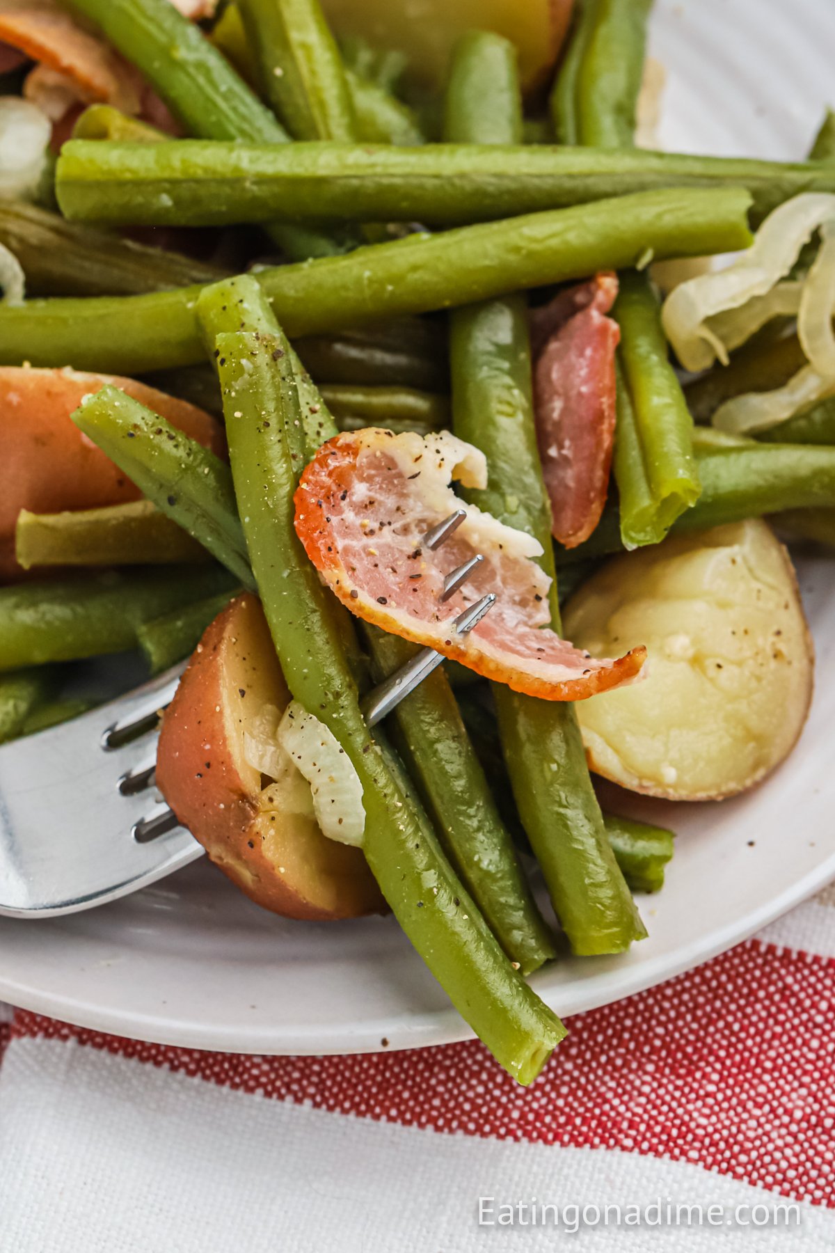 Green and potatoes on a white plate with a serving on a fork