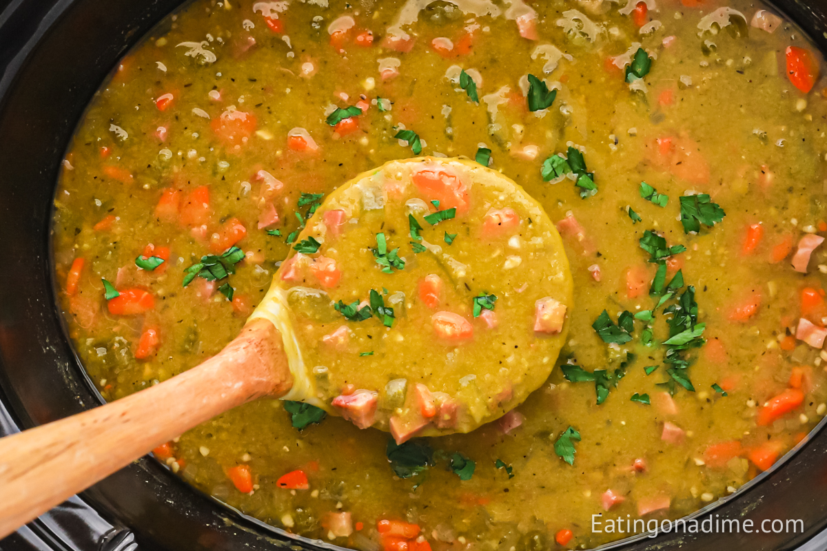 Split pea soup in the slow cooker with a serving on a ladle