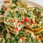 A close-up of several spinach and red pepper egg muffins stacked on a plate, with one muffin showing a bite revealing its fluffy texture and colorful vegetables—just like a homemade Starbucks Egg White Bites recipe.
