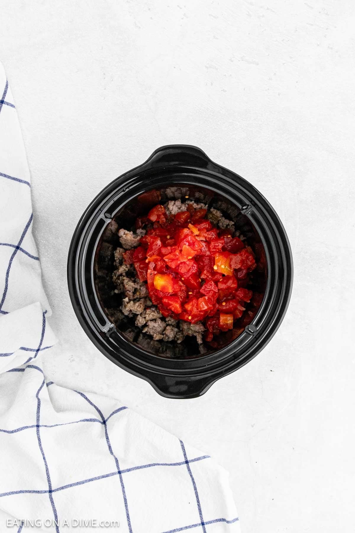 Rotel poured over the top of the cooked sausage in the crockpot.