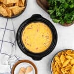 Sausage Cheese Dip in a mini crock pot with a small bowls of chips on the side.