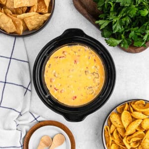 Sausage Cheese Dip in a mini crock pot with a small bowls of chips on the side.