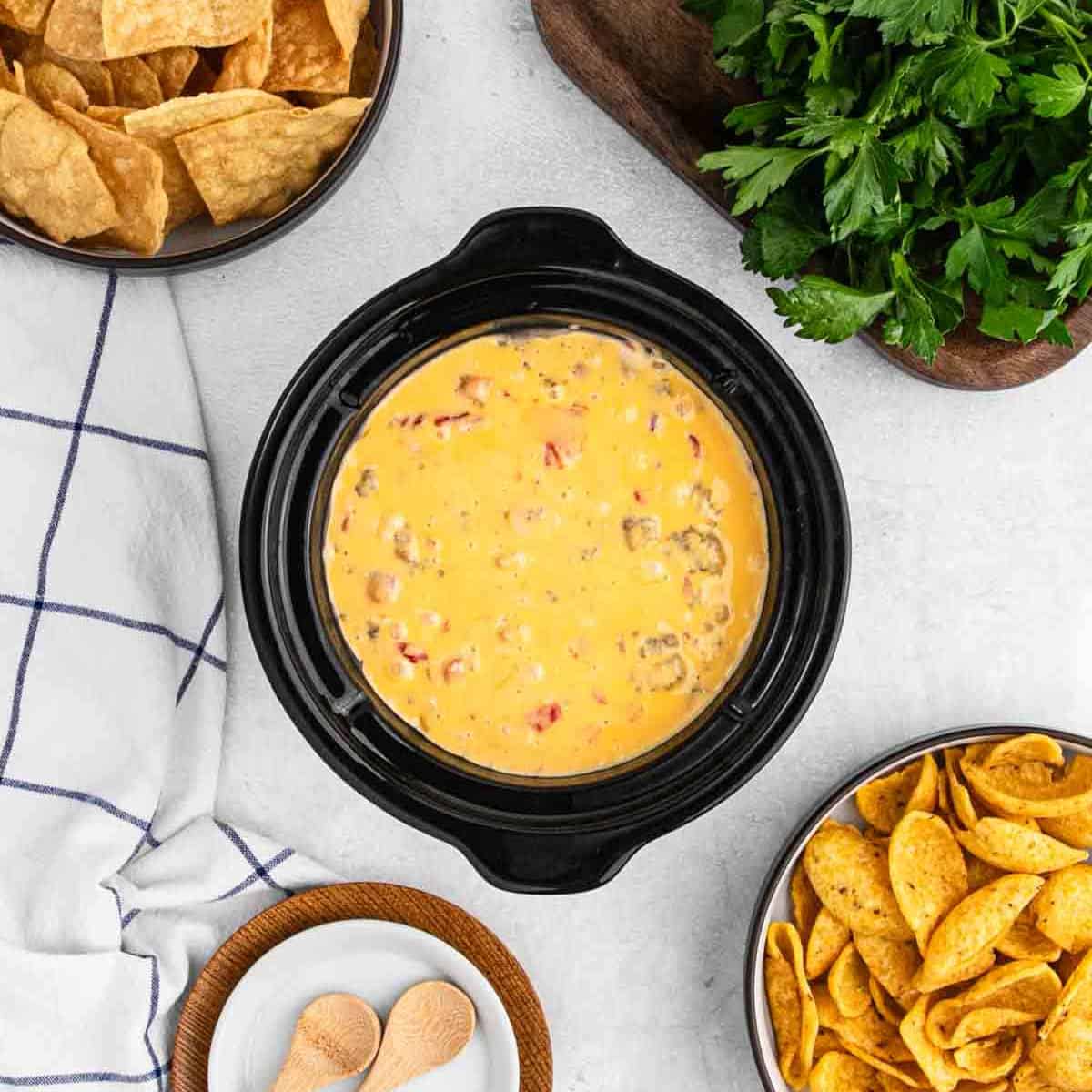 Sausage Cheese Dip in a mini crock pot with a small bowls of chips on the side.