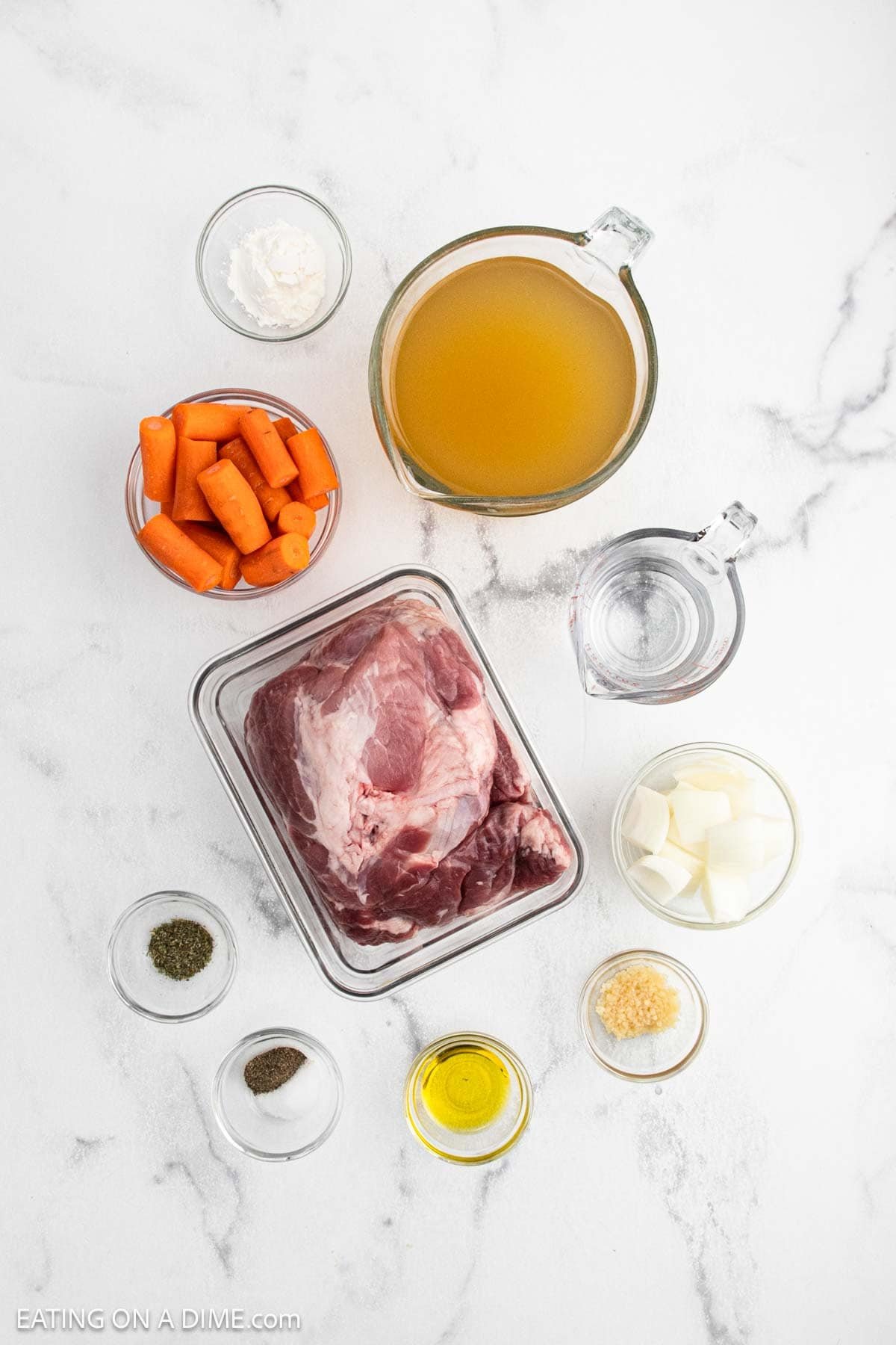 Ingredients for Instant Pot Pork Roast—raw pork shoulder, chopped carrots, onion, minced garlic, broth, water, olive oil, black pepper, Italian seasoning, and cornstarch—are arranged in small glass bowls on a white marble surface.
