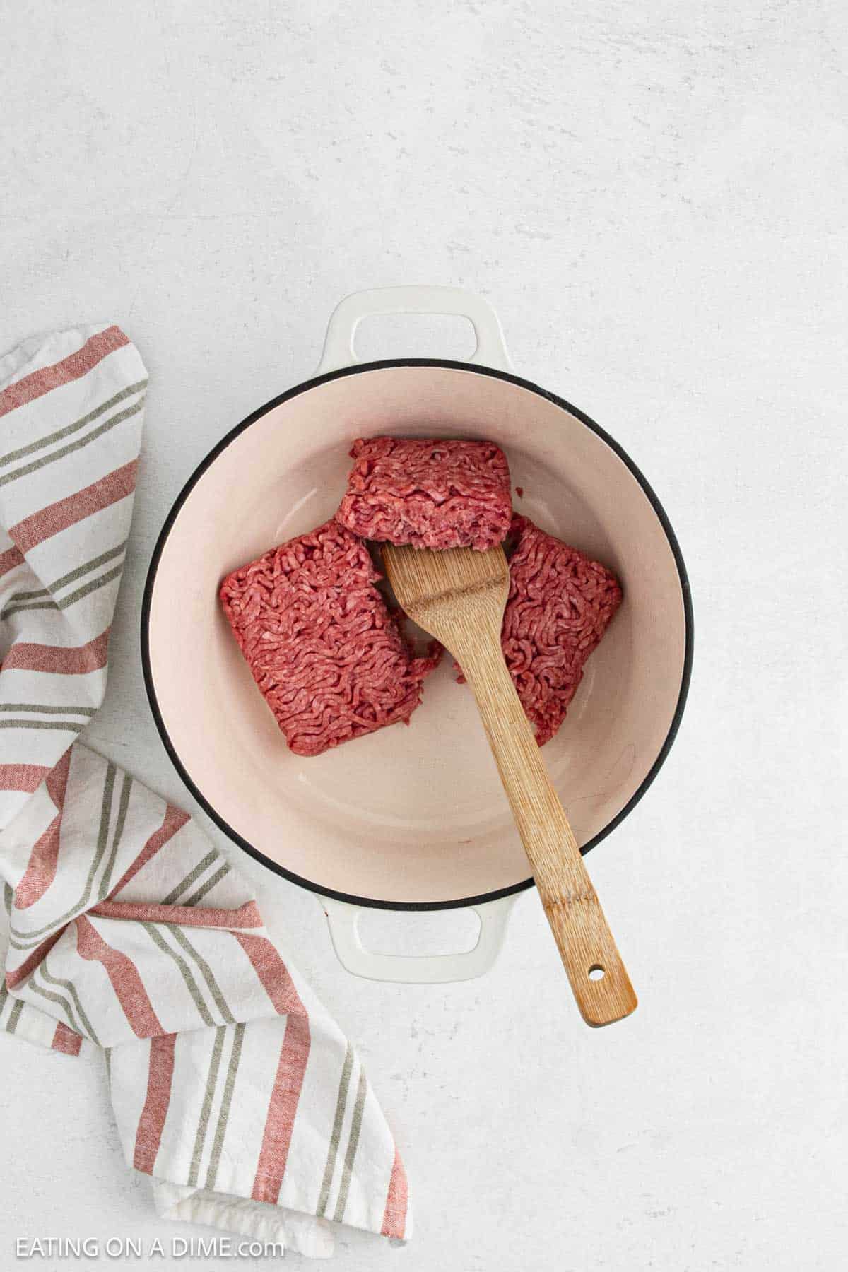 Cooking ground beef in a large pot with a wooden spoon.