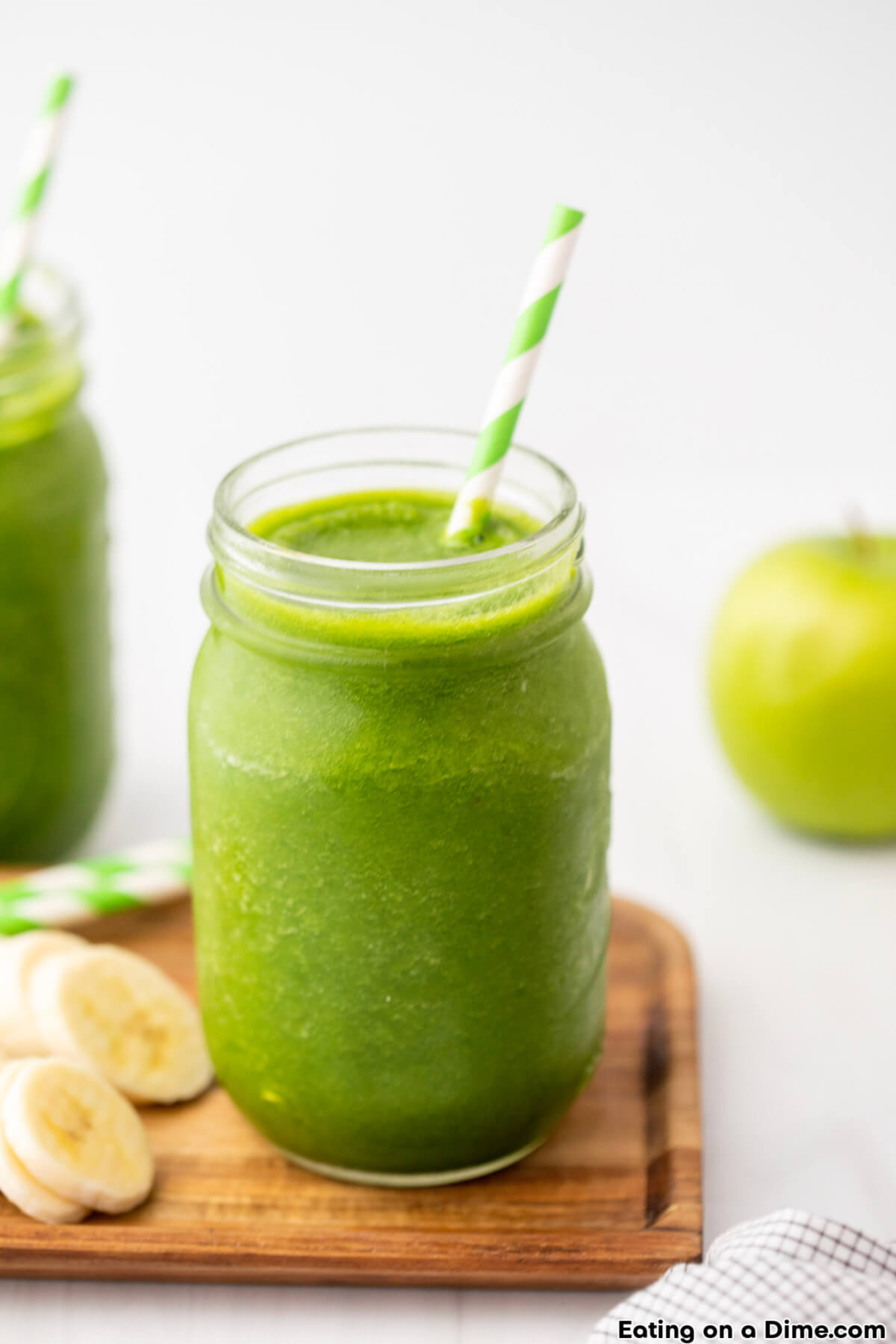 Green Smoothie in a mason jar with a striped straw with slice bananas
