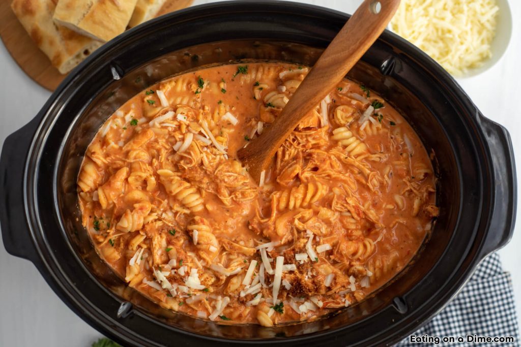 Chicken Parmesan Soup in the slow cooker with a wooden spoon