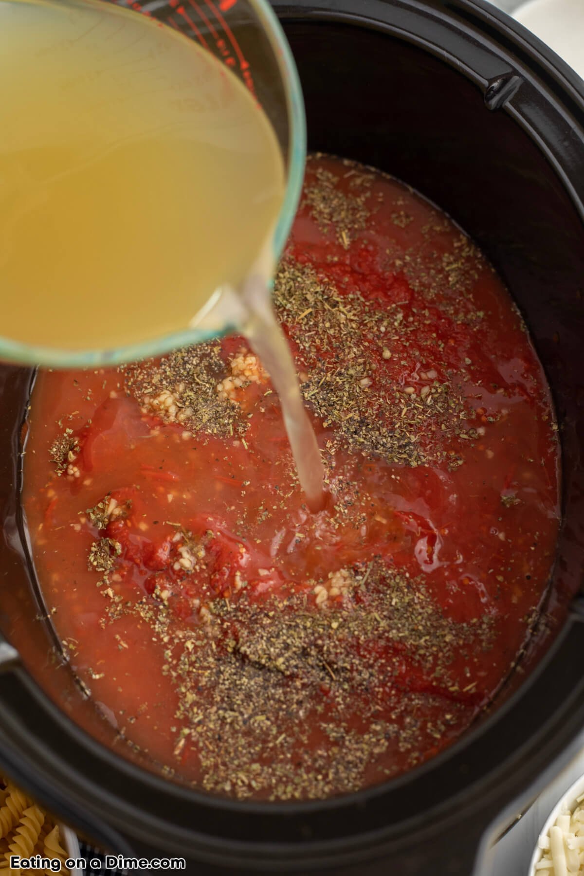 Pouring the chicken broth in the slow cooker with the other ingredients