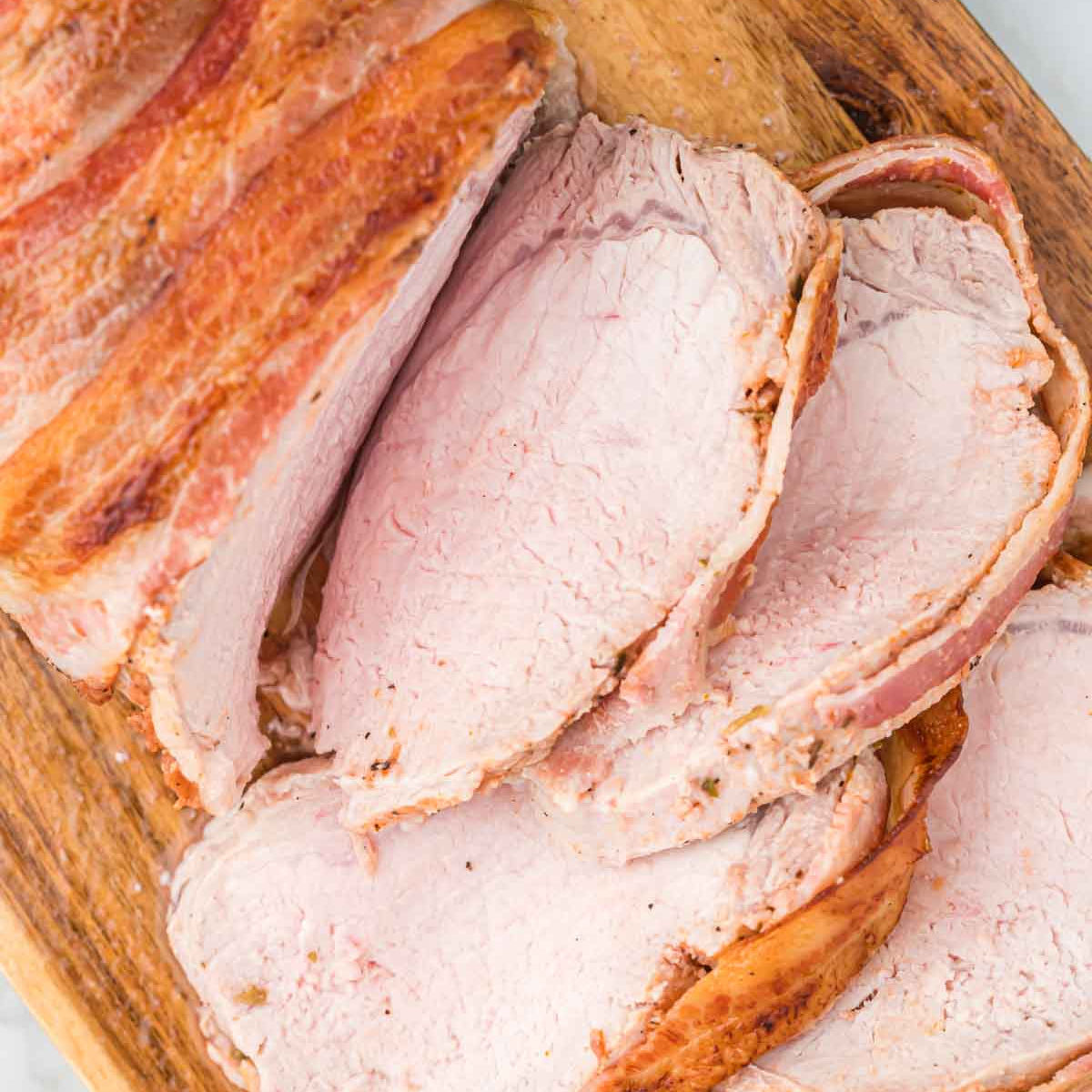 Sliced Bacon Wrapped Pork Loin on a cutting board